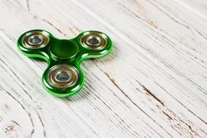 Green fidget spinner stress relieving toy on wood background photo