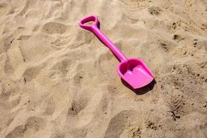 juguete de arena rosa la playa. dia de vacaciones foto