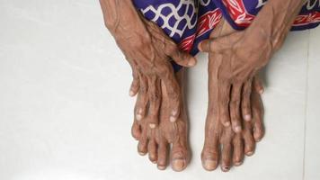 Eine ältere Person, die auf dem Boden sitzt, berührt die Füße mit den Händen video