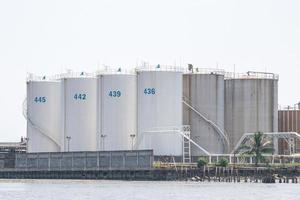 large white liquid chemical storage tanks by the sea. photo