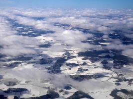 Aerial view of white snowscape and cloudscape covering landscape below in winter, wallpaper, in white, Scandinavia, arctic circle photo