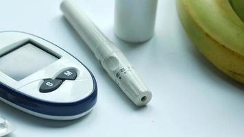 Digital blood sugar monitor on table with finger prick device and bananas video