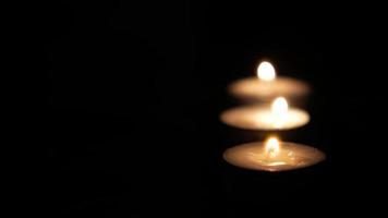 Three lit candles in dark scene video