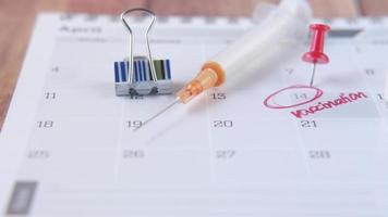 een seringe en een papier kalender met vaccinatie gemarkeerd video