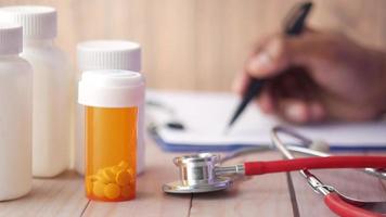 Doctor writes a perscription, scene with a stethoscope and pills containers video