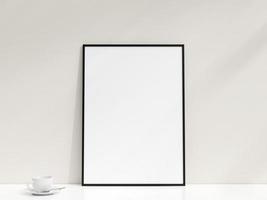 Interior poster mockup with photo frame leaning against the white wall. Minimalist photo frame mockup. Empty frame stands on white table. 3d rendering.