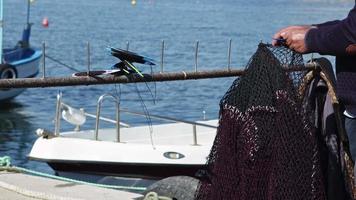 pescador consertando suas redes na praia video