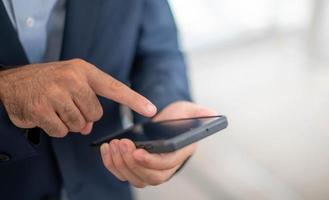 mano masculina tocando y mirando un teléfono inteligente para buscar y encontrar algo para usar, o prepararse para pagar con el sistema de pago electrónico en su teléfono. foto