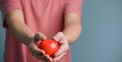 Hands holding and giving red heart for love, health care, organ donation, world heart day, world health day, mindfulness, well being, family insurance concept. photo