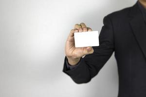 A smart Man holding mock-up white card on white background, a business man wearing dark suit and his hand holding white card photo
