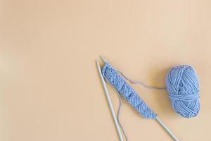 Top view of gray knitting wool and knitting needles on pastel orange background. photo