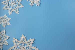 Top view of handmade white crochet  snowflakes on blue background. Merry Christmas and happy new year concept. photo