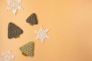 Top view of handmade white crochet  snowflakes and christmas tree on orange pastel background. Merry Christmas and happy new year concept. photo