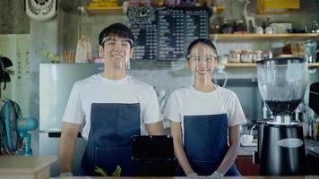 o dono da cafeteria, um casal de homens e mulheres, sorrindo e acenando para dar as boas-vindas aos clientes. pelo ponto de vista olhando para a câmera video