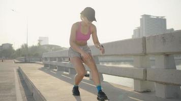 Motivated attractive sporty fit female runner tying shoelaces on training shoes and jogging in city street in early morning. Muscular athlete woman running near multistorey buildings. video
