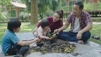 een gezin van twee zonen helpt bij het uitvoeren van stukjes fruit en groenten om te leren hoe ze natuurlijke compost kunnen maken. in de voortuin op vakantie video