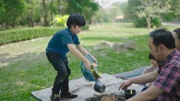 Ein Sohn der Familie trägt Obst- und Gemüsereste aus, um zu lernen, wie man natürlichen Kompost herstellt. im Vorgarten an Feiertagen video