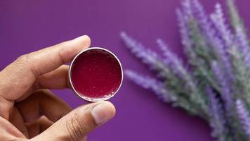 Showing a small container with red product, cosmetic, lavender on the background video