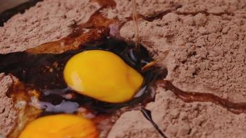 ovo de galinha cai em câmera lenta em close-up de farinha de cacau. receita passo a passo para fazer biscoitos de chocolate caseiros ou bolo de brownies. video