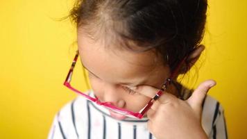 Little girl with glasses rubs eye video