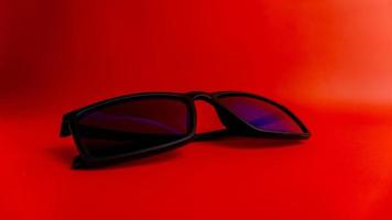 Black sunglasses on red background photo