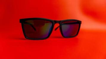 Black sunglasses on red background photo