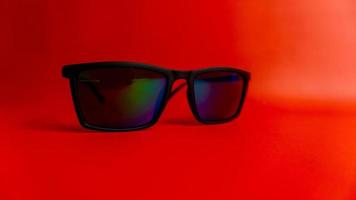 Black sunglasses on red background photo