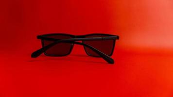 Black sunglasses on red background photo