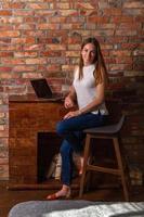 mujer sonriente sentada en una silla alta con una computadora portátil detrás de ella foto