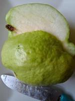 Crystal guava fruit that is split into two parts using a kitchen knife photo