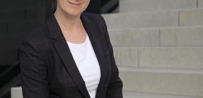Female professional in a white shirt and black suit jacket with an urban background photo