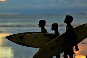 Kids walking with surfing board before sunset photo