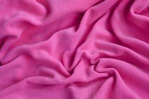 The blanket of furry pink fleece fabric. A background of light pink soft plush fleece material with a lot of relief folds photo