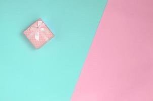 Small pink gift box lie on texture background of fashion pastel blue and pink colors paper in minimal concept photo