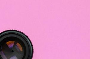 Camera lens with a closed aperture lie on texture background of fashion pastel pink color paper in minimal concept photo