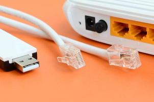 Internet router, portable USB wi-fi adapter and internet cable plugs lie on a bright orange background. Items required for internet connection photo