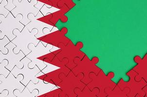 Bahrain flag is depicted on a completed jigsaw puzzle with free green copy space on the right side photo