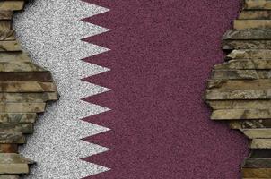 Qatar flag depicted in paint colors on old stone wall closeup. Textured banner on rock wall background photo