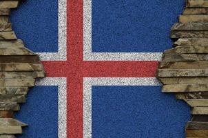 Iceland flag depicted in paint colors on old stone wall closeup. Textured banner on rock wall background photo