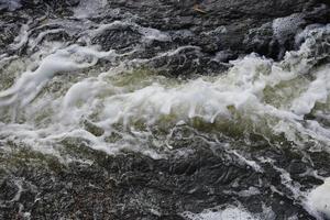 Waves of water of the river and the sea meet each other during high tide and low tide. Deep blue stormy sea water surface with white foam and waves pattern, background photo