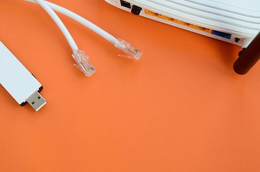 Internet router, portable USB wi-fi adapter and internet cable plugs lie on a bright orange background. Items required for internet connection photo