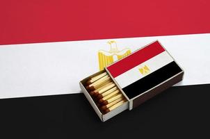 Egypt flag is shown in an open matchbox, which is filled with matches and lies on a large flag photo