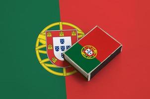 Portugal flag is pictured on a matchbox that lies on a large flag photo