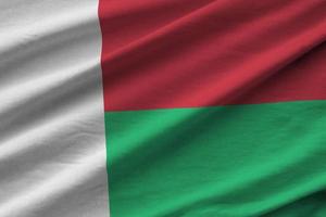Madagascar flag with big folds waving close up under the studio light indoors. The official symbols and colors in banner photo