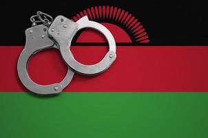 Malawi flag and police handcuffs. The concept of crime and offenses in the country photo