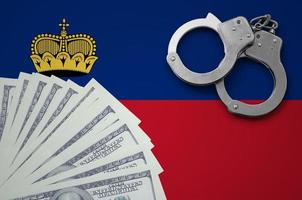 Liechtenstein flag with handcuffs and a bundle of dollars. The concept of illegal banking operations in US currency photo
