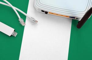 Nigeria flag depicted on table with internet rj45 cable, wireless usb wifi adapter and router. Internet connection concept photo