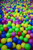 Many colorful plastic balls in a kids' ballpit at a playground. Close up pattern photo