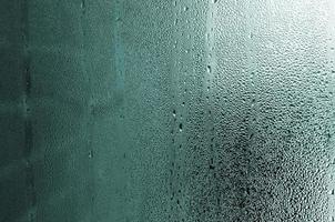 Texture of a drop of rain on a glass wet transparent background. Toned in turquoise color photo