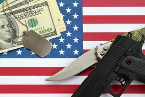 Close up dollar money with weapons and military badges on United States flag. Military forces, financing and national service concept photo